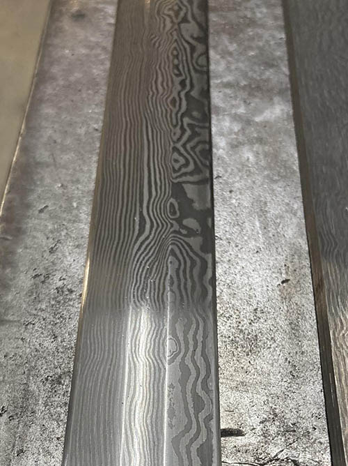 A bar of Damascus steel being shaped into a sword blade.